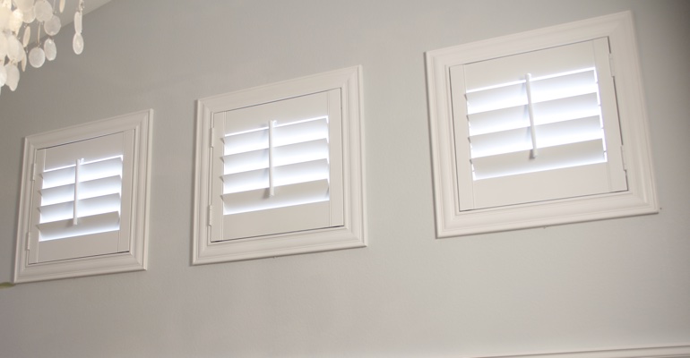 Shutters on three small square windows in laundry room